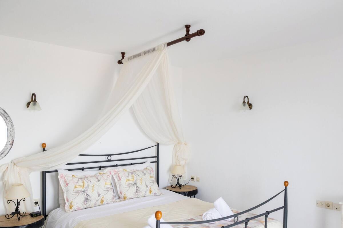 Une chambre à coucher avec un lit à baldaquin, des tables de chevet, un miroir et une commode.