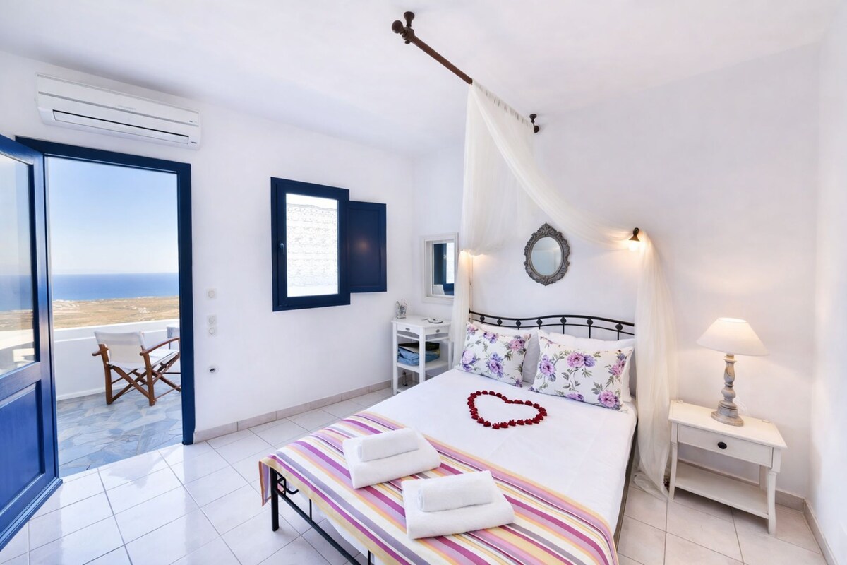 A bedroom with a bed, bedside table, and a view of the sea.