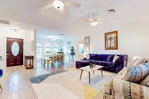 A spacious living room with a sofa, a coffee table, and a dining area with a table and chairs. - Fantastic waterfront escape with hot tub, lanai, boat lift, WiFi & central AC (Bonita Springs)