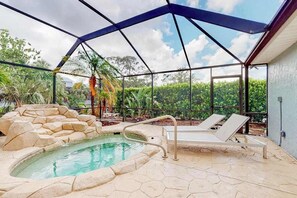 A swimming pool with a stone border, lounge chairs, and a covered area with a metal roof. - Fantastic waterfront escape with hot tub, lanai, boat lift, WiFi & central AC (Bonita Springs)