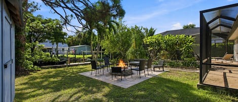 Un jardin avec un foyer extérieur, du mobilier de jardin et un espace patio.