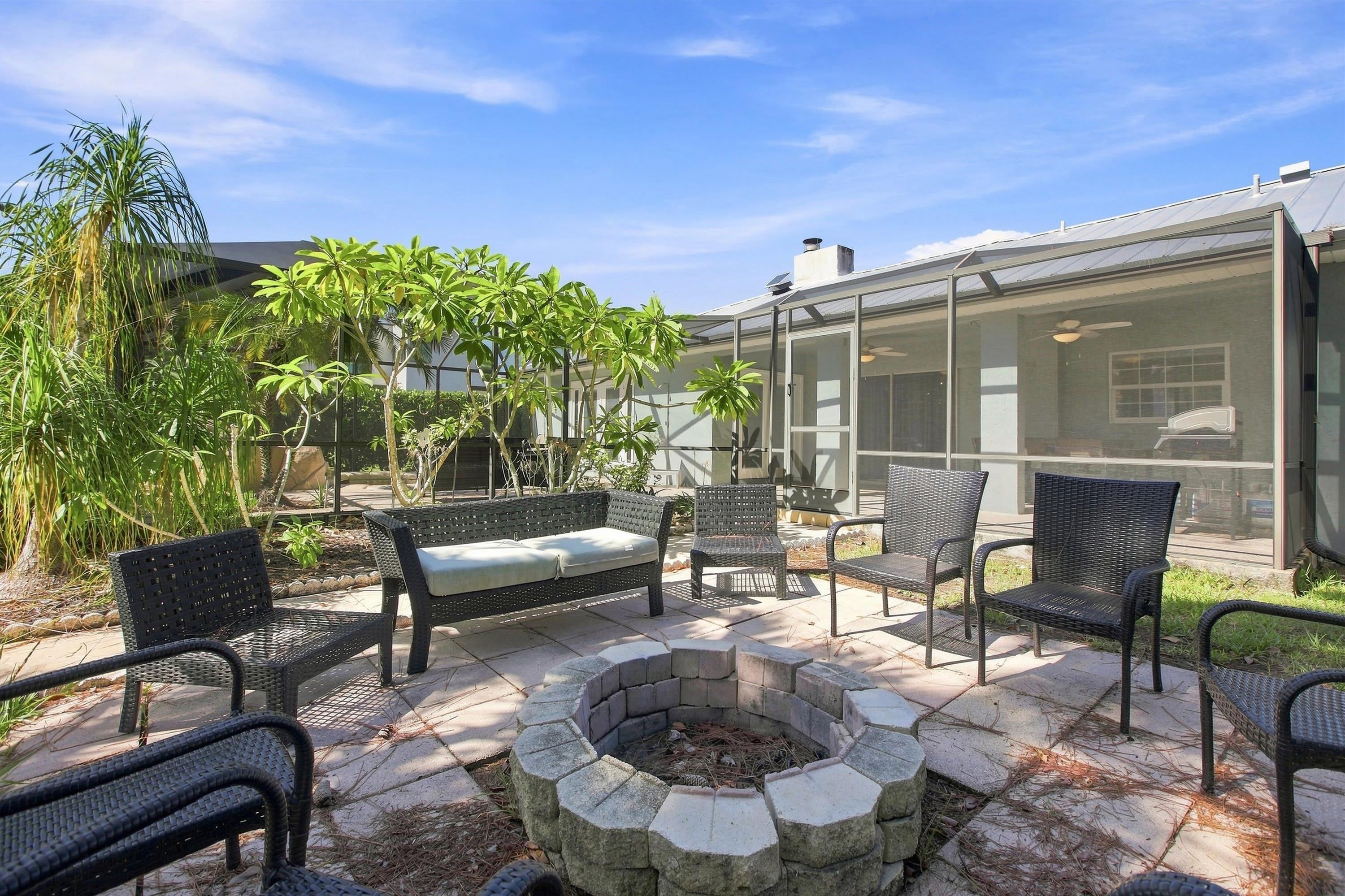 A patio area with outdoor furniture, a fire pit, and a glass-enclosed structure.