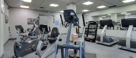Une salle de sport équipée de machines de cardio, de machines de musculation et dotée d’un mur recouvert de miroirs.