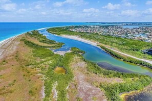 An aerial view of a coastal area with a curving waterway, green vegetation, and a distant urban settlement. - Waterview condo with shared pool, panoramic balcony views, and WIFI (Marco Island)