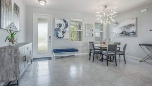 A modern dining area with a round table, chairs, a bench, and artwork on the walls. - Contemporary Getaway with an Enclosed Yard, Fast WiFi, & Furnished Lanai (Bonita Springs)