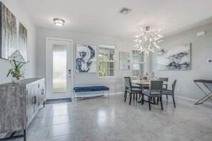 A modern dining area with a round table, chairs, a bench, and artwork on the walls. - Contemporary Getaway with an Enclosed Yard, Fast WiFi, & Furnished Lanai (Bonita Springs)