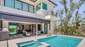A modern two-story house with a swimming pool, outdoor seating, and a balcony.