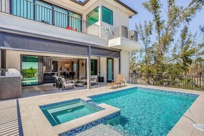 A modern two-story house with a swimming pool, outdoor seating, and a balcony. - Spacious modern home close to beach with pool, central AC, & washer/dryer (Bonita Springs)