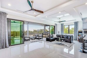 A spacious living area with a modern design, featuring a large sofa, a coffee table, and a ceiling fan. - Spacious modern home close to beach with pool, central AC, & washer/dryer (Bonita Springs)