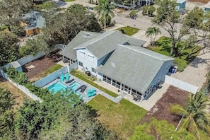 A large house with a swimming pool, surrounded by trees and a well-maintained lawn. - Charming getaway in prime location with fast WiFi, W/D, and central AC (Bonita Springs)