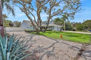 A house with a front yard, a driveway, and a fire hydrant. - Charming getaway in prime location with fast WiFi, W/D, and central AC (Bonita Springs)