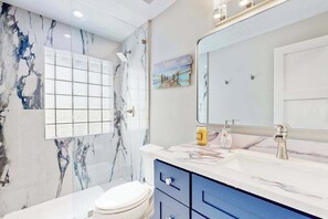 Un bagno con parete in marmo, uno specchio grande, un lavabo con rubinetto e un water.
