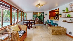 A room with a dining area, kitchen, and large windows. - Bali-inspired coastal home w/private pool, spa, and tiki room (Cape Coral)