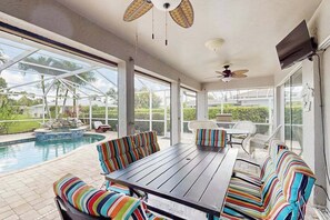 Überdachte Terrasse mit Pool, Sitzgelegenheiten im Freien und Deckenventilator.