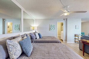 Ein Schlafzimmer mit einem großen Bett, einem Deckenventilator und einem Spiegel.