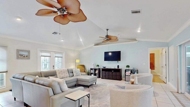 A spacious living room with a sectional sofa, a round ottoman, a flat-screen TV, and ceiling fans. - Canal-front Cape Coral oasis w/ private pool, hot tub & Dog friendly (Cape Coral)