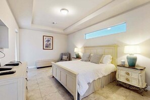 A bedroom with a large bed, two bedside tables with lamps, a chair, a dresser, and a framed picture on the wall. - Desirable SW Home | Private Heated Saltwater Pool | Newly Built in 2019 (Cape Coral)