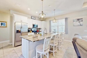 A modern kitchen with a central island, white cabinetry, stainless steel appliances, and pendant lighting. - Desirable SW Home | Private Heated Saltwater Pool | Newly Built in 2019 (Cape Coral)