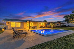 A residential house with a swimming pool, outdoor seating, and a well-lit patio area. - Updated Waterfront Escape | Dock & Easy Gulf Access | Walk to Beach & Tennis (Cape Coral)