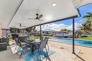 Eine Außenpatio mit Pool, überdachter Sitzgelegenheit und Deckenventilatoren.