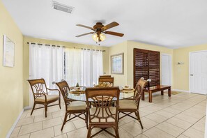 A dining area with a round table, six chairs, a ceiling fan, and a window with curtains. - Open-Air Waterfront Retreat | Private Pool (Cape Coral)