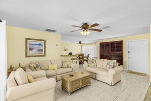 A living room with two sofas, a coffee table, a ceiling fan, and a dining area with chairs and a table. - Open-Air Waterfront Retreat | Private Pool (Cape Coral)