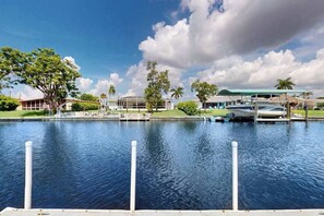 A waterfront property with a dock, a swimming pool, and a building with a green roof. - Waterfront home with heated pool, dock, & kayaks - minutes to beach (Cape Coral)