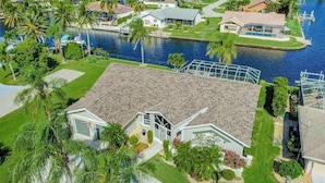 A residential property with a large house, a swimming pool, and a river. - Stunning waterfront snowbird escape with private saltwater pool, dock, AC & W/D (Cape Coral)