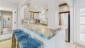 A modern kitchen with a central island, bar stools, and stainless steel appliances. - Friendly Canalfront Home with Private Pool, High-Speed WiFi - Snowbird-Friendly (Cape Coral)