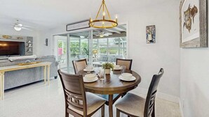 A dining area with a round table, chairs, and a chandelier. There is a sofa and a television in the adjacent living room. - Friendly Canalfront Home with Private Pool, High-Speed WiFi - Snowbird-Friendly (Cape Coral)