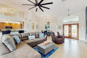 A spacious living area with a sectional sofa, a grey ottoman, and a ceiling fan. - Wonderful oasis w/lanai, private pool, tropical bar, private dock, Gulf access (Cape Coral)