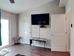 Ein Zimmer mit einem an der Wand befestigten Fernseher, einer Sitzbank und zwei Türen.