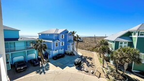Ein zweistöckiges Haus mit blauer Fassade, einer überdachten Auffahrt und Blick auf den Strand.