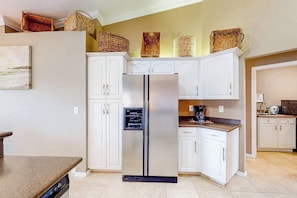 A kitchen with white cabinets, a stainless steel refrigerator, and wicker baskets on the upper cabinets. - Inviting home with pool, water view, enclosed yard, central AC, W/D (Cape Coral)