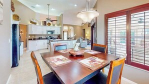 A dining area with a wooden table, chairs, and a hanging light fixture. - Inviting home with pool, water view, enclosed yard, central AC, W/D (Cape Coral)