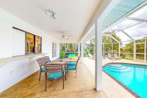 A covered patio with a pool, outdoor furniture, and a view of the surrounding greenery. - Water-view home with enclosed private pool, grill, scenic balcony, AC & W/D (Cape Coral)
