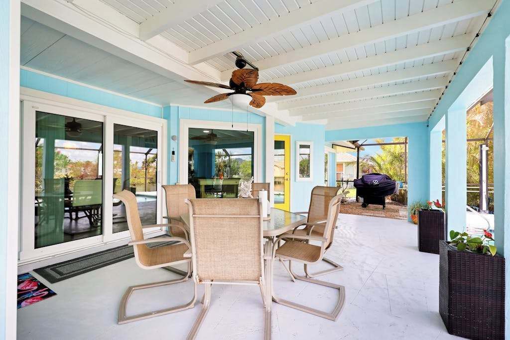 Un patio couvert avec un ventilateur de plafond, des portes vitrées et du mobilier d’extérieur.