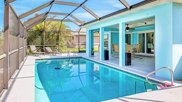 Una piscina con zona techada, sillas de descanso y vistas despejadas al exterior.