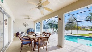 A covered patio with a pool, outdoor furniture, and ceiling fans. - Spacious Lakefront Home with a Screened-In Pool in Exclusive Community (Fort Myers)