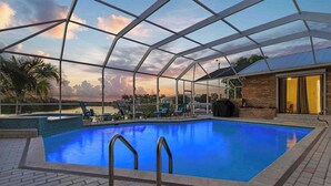 Piscina com cobertura de vidro, rodeada por espreguiçadeiras e um pátio de tijolos.