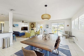 A spacious living area with a dining table, chairs, a sofa, and a television. - Relaxing retreat with private pool, washer/dryer, & family-friendly amenities (Cape Coral)