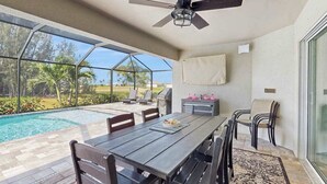 Eine Außenpatio mit Pool, Esstisch, Stühlen und Deckenventilator.