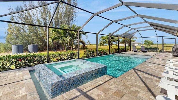 Ein überdachter Außenpool mit Glasboden, umgeben von einer Metallkonstruktion, und eine Terrasse mit Liegestühlen.