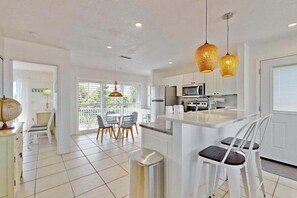 A modern kitchen with white cabinets, a central island, and pendant lighting. - Beautiful duplex with private W/D, WiFi, & close to the beach (Englewood)