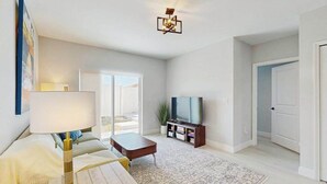 A modern living room with a sofa, coffee table, TV, and a patterned rug. - Coastal duplex with internet, washer and dryer, and dog friendly (Englewood)