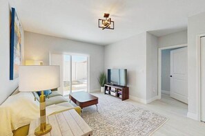 A modern living room with a sofa, coffee table, TV, and a patterned rug. - Coastal duplex with internet, washer and dryer, and dog friendly (Englewood)