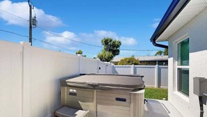 A hot tub with steps, a white fence, and a house with a green window. - Coastal duplex with internet, washer and dryer, and dog friendly (Englewood)