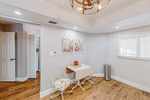 A room with a white table, two chairs, a ceiling light fixture, and a window with blinds. - Waterfront condo with balcony, pool, pickball/tennis, & walking paths (Fort Myers)