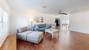 A spacious living room with a sofa, ottoman, coffee table, and a dining area with chairs and a table. - Bright and airy home with enclosed pool, hammock, and open-concept interior (Fort Myers)