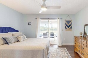 A bedroom with a bed, a ceiling fan, a dresser, and a view through a glass door. - Renovated dog-friendly home near beach with private pool, screened lanai, grill (Englewood)